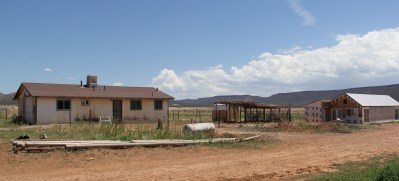On the left is the home that is being remodeled through First Nations funding, to provide offices and a space to clean and store produce. On the right is a passive solar greenhouse currently being built. The greenhouse is designed so that in the fall and winter, the sun's rays are absorbed by a thermal wall in the back of the greenhouse, which will then release the heat overnight.  Photo by Angelo Baca