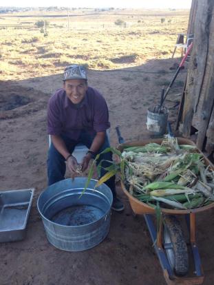 Ty Tsosie husking corn. September 28. Photo by Roberto Nutlouis
