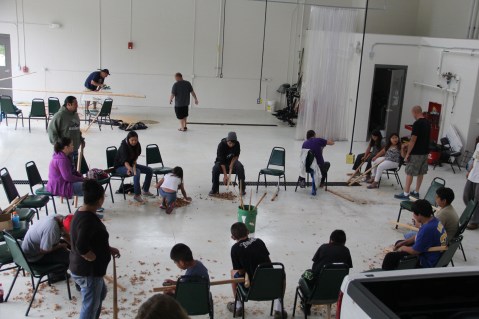 Group of Bad River youth and family members, carving rice knockers. Photo by Angelo Baca