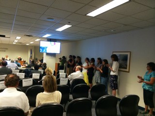 Inside the PUC hearing, where supporters stood out of respect for Michael Dahl's testimony. On the screen you can see the berry pickers' blueberries that Michael brought up with him to show the commission. Photo by Angelo Baca