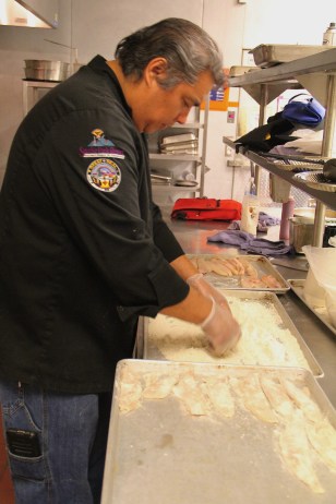 Arlie breading walleye donated by the Red Lake tribe, in finely ground Oneida white corn flour. Photo by Elizabeth Hoover