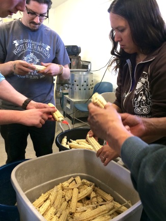Rowen and Zach Paige from the White Earth Land Recovery Project, teaching workshop participants how to select seed corn. Photo by Elizabeth Hoover